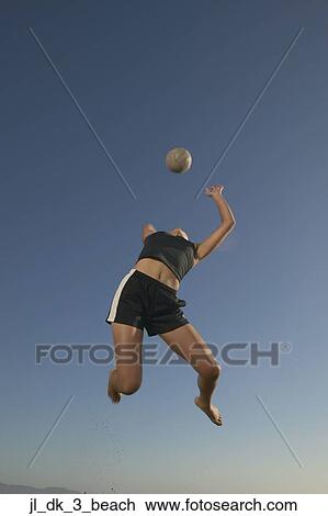Low angle view of a young woman jumping up in the air reaching out for a volleyball View Large Photo Image Stock Image - Low angle view of a young woman jumping up in the air reaching out for a volleyball. Fotosearch