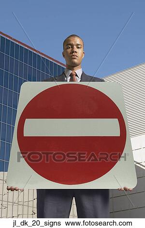 Portrait of a young man holding a no entry signboard View Large Photo Image Stock Photograph - Portrait of a young man holding a no entry signboard. Fotosearch