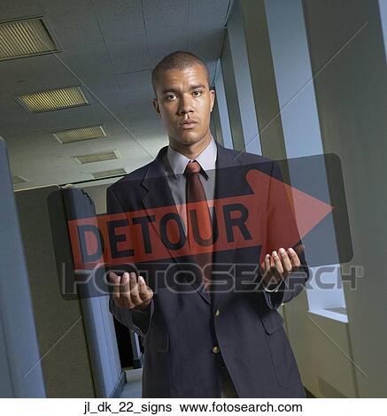 Portrait of a young man holding a detour signboard View Large Photo Image Stock Photograph - Portrait of a young man holding a detour signboard. Fotosearch