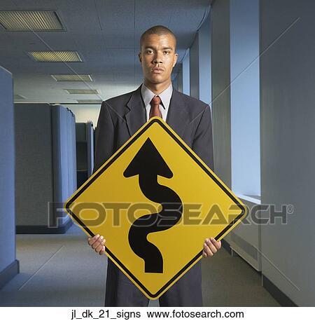 Portrait of young man holding a curved road ahead signboard View Large Photo Image Stock Photograph - Portrait of young man holding a curved road ahead signboard. Fotosearch