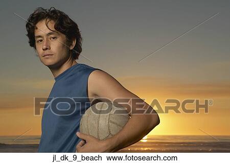 Side profile of a young man holding a volleyball under his arm View Large Photo Image Stock Image - Side profile of a young man holding a volleyball under his arm. Fotosearch