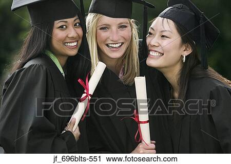 Stock Image - Three young female graduates standing together holding diplomas smiling. Fotosearch