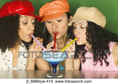 Picture - Three young women drinking a cocktail. Fotosearch