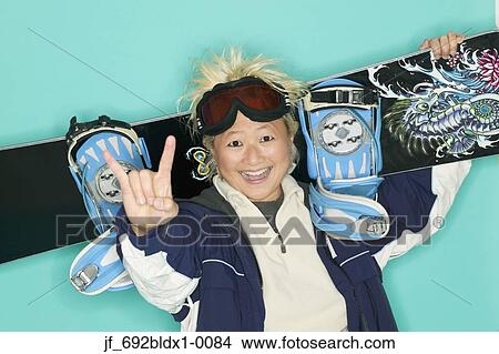 Picture - Woman holding a snowboard looking at camera smiling. Fotosearch