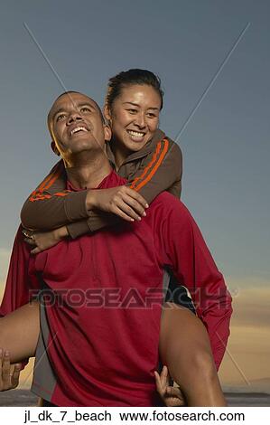 Young man carrying a young woman on his back View Large Photo Image Stock Image - Young man carrying a young woman on his back. Fotosearch