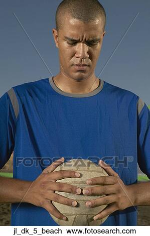 Stock Image - Young man holding a volley ball between his hands. Fotosearch