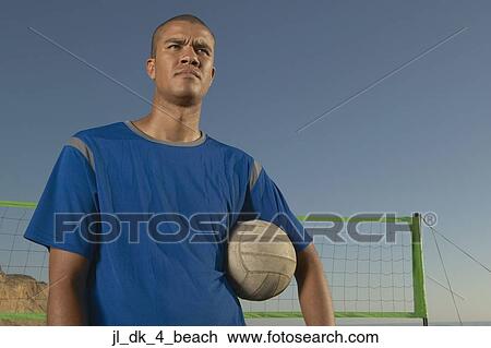 Young man holding a volleyball under his arm View Large Photo Image Stock Image - Young man holding a volleyball under his arm. Fotosearch