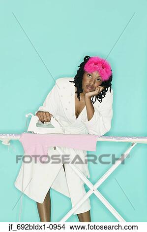 Picture - Young woman ironing looking at camera. Fotosearch