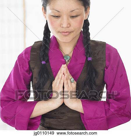 Stock Photo - Young woman standing with hands together. Fotosearch