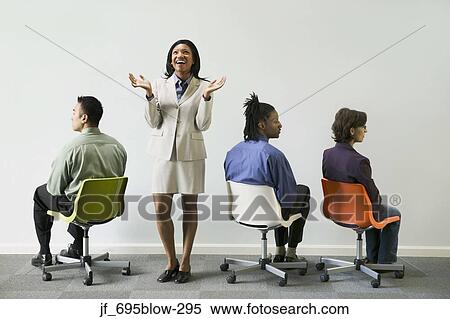 Businesswoman standing with three business executives sitting on chairs View Large Photo Image Stock Photography - Businesswoman standing with three business executives sitting on chairs. Fotosearch