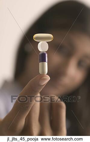 Close-up of tower of capsules and a tablet balanced on a young woman's fingertip View Large Photo Image Stock Image - Close-up of tower of capsules and a tablet balanced on a young woman's fingertip. Fotosearch