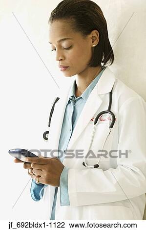 Female doctor operating a hand held device View Large Photo Image Stock Image - Female doctor operating a hand held device. Fotosearch