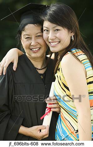 Female graduate and a young woman standing together holding a diploma smiling View Large Photo Image Stock Photo - Female graduate and a young woman standing together holding a diploma smiling. Fotosearch
