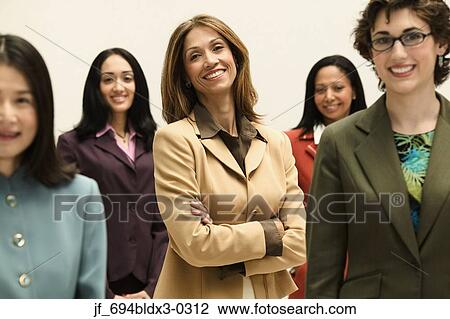 Group of young businesswomen standing together looking at camera smiling View Large Photo Image Stock Image - Group of young businesswomen standing together looking at camera smiling. Fotosearch