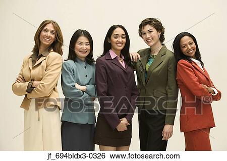 Group of young businesswomen standing together looking at camera smiling View Large Photo Image Stock Photograph - Group of young businesswomen standing together looking at camera smiling. Fotosearch