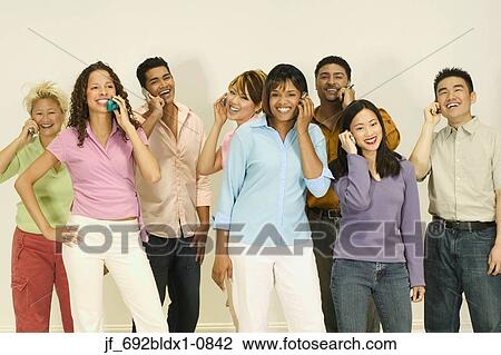 Stock Image - Group of young people standing together talking on mobile phones. Fotosearch