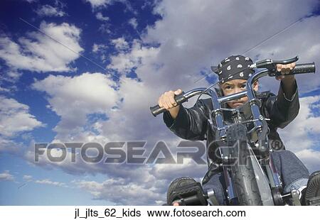 Low angle view of a young boy riding a toy motorcycle View Large Photo Image Stock Photograph - Low angle view of a young boy riding a toy motorcycle. Fotosearch