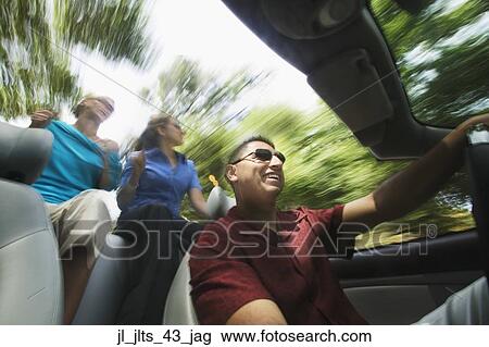 Low angle view of a young man driving a young couple in a convertible car View Large Photo Image Stock Image - Low angle view of a young man driving a young couple in a convertible car. Fotosearch