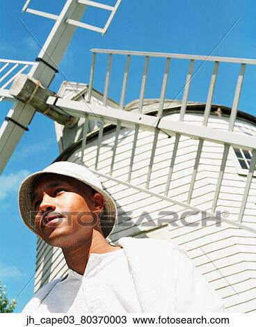 Low angle view of a young man standing near a windmill View Large Photo Image Stock Image - Low angle view of a young man standing near a windmill. Fotosearch