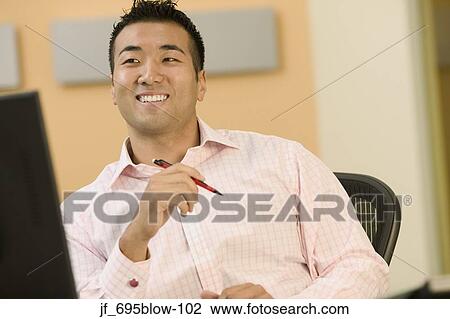Portrait of a businessman looking at a computer screen smiling View Large Photo Image Stock Image - Portrait of a businessman looking at a computer screen smiling. Fotosearch