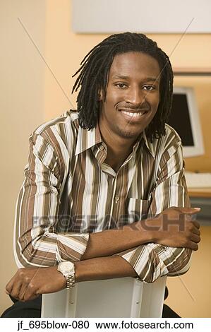 Portrait of a businessman sitting on a chair looking at camera smiling View Large Photo Image Stock Image - Portrait of a businessman sitting on a chair looking at camera smiling. Fotosearch
