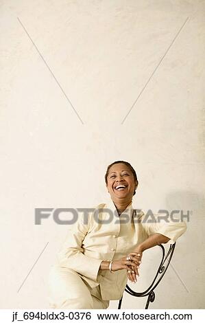 Portrait of a businesswoman sitting on a chair smiling View Large Photo Image Stock Photograph - Portrait of a businesswoman sitting on a chair smiling. Fotosearch