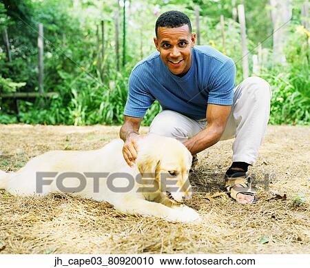 Stock Image - Portrait of a mid adult man petting a pet dog. Fotosearch