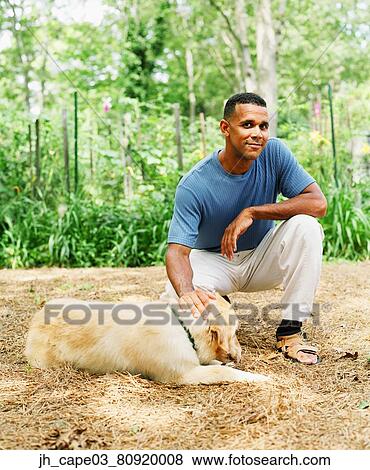 Stock Photo - Portrait of a mid adult man petting a pet dog. Fotosearch