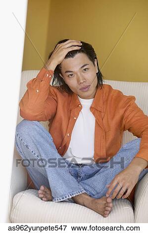 Portrait of a young man sitting on a couch View Large Photo Image Stock Photo - Portrait of a young man sitting on a couch. Fotosearch