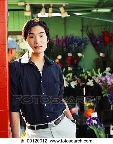 Portrait of a young man standing in a flower shop View Large Photo Image Stock Image - Portrait of a young man standing in a flower shop. Fotosearch