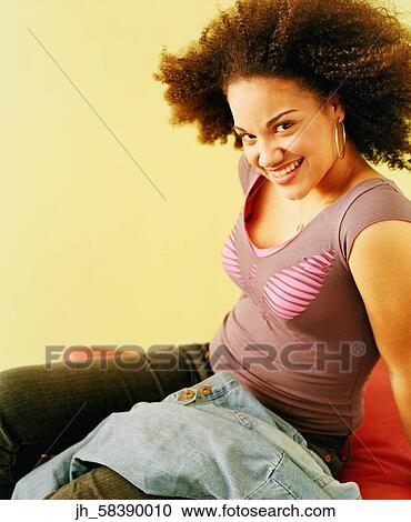 Portrait of a young woman sitting and smiling View Large Photo Image Stock Image - Portrait of a young woman sitting and smiling. Fotosearch