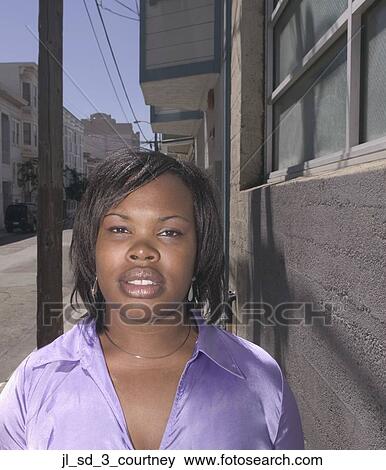 Portrait of a young woman standing on a sidewalk View Large Photo Image Stock Photo - Portrait of a young woman standing on a sidewalk. Fotosearch