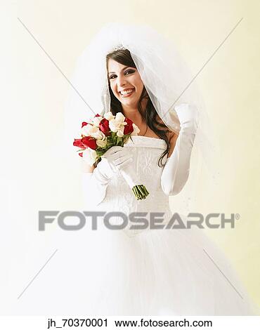 Portrait of a young woman wearing bridal outfit holding a bouquet of roses View Large Photo Image Stock Image - Portrait of a young woman wearing bridal outfit holding a bouquet of roses. Fotosearch