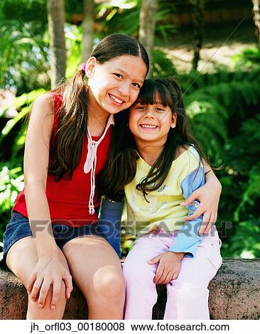 Stock Photo - Portrait of two young girls looking at camera smiling. Fotosearch