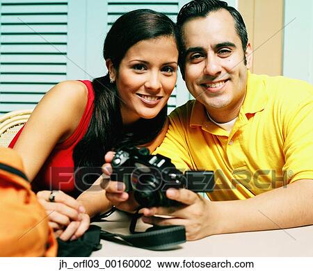 Stock Image - Portrait of young couple looking at camera smiling. Fotosearch