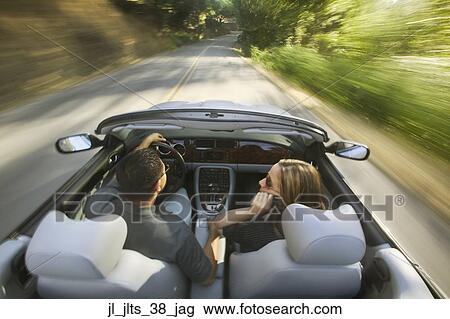 Rear view of a young couple driving in a convertible car View Large Photo Image Stock Image - Rear view of a young couple driving in a convertible car. Fotosearch