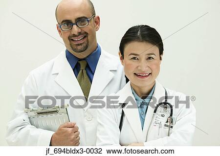 Stock Image - Two doctors looking at camera smiling. Fotosearch