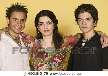 Stock Photo - Two young men and a young woman standing together looking at camera. Fotosearch