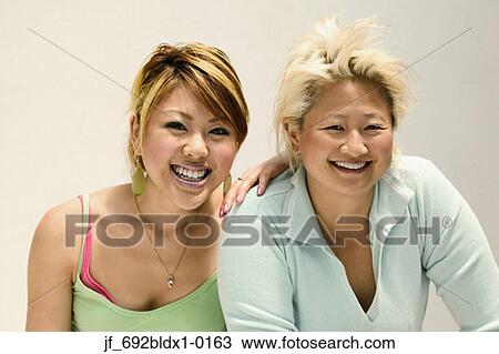 Two young women looking at camera smiling View Large Photo Image Stock Image - Two young women looking at camera smiling. Fotosearch