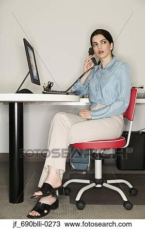 Woman sitting at a desk in an office View Large Photo Image Stock Image - Woman sitting at a desk in an office. Fotosearch