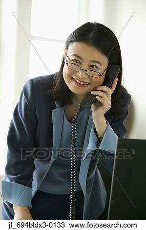 Stock Image - Woman talking on a phone smiling. Fotosearch