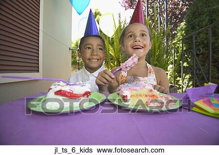 Stock Photograph - Young boy and girl eating cake at a birthday party. Fotosearch