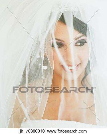 Stock Image - Young bride wearing a wedding gown smiling. Fotosearch