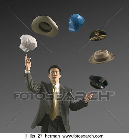 Picture - Young businessman juggling assorted hats. Fotosearch