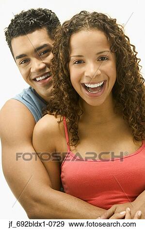 Stock Photo - Young couple holding each other looking at camera smiling. Fotosearch