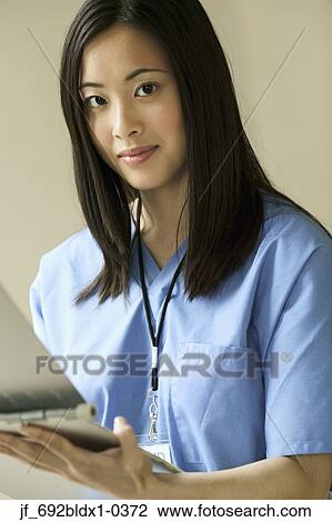 Young female doctor holding a clipboard looking at camera View Large Photo Image Stock Image - Young female doctor holding a clipboard looking at camera. Fotosearch