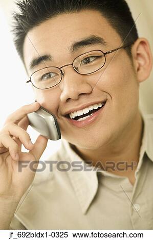 Stock Photography - Young man smiling talking on a mobile phone. Fotosearch