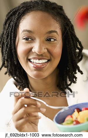 Young woman eating with a fork from a bowl View Large Photo Image Stock Image - Young woman eating with a fork from a bowl. Fotosearch