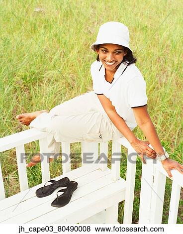 Stock Photo - Young woman sitting on a railing. Fotosearch