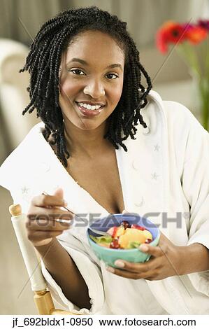 Stock Image - Young woman smiling holding a bowl of food. Fotosearch